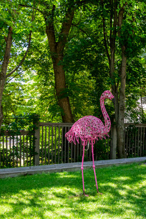 Pink flamingo in the garden on the background of green grass and treesの写真素材