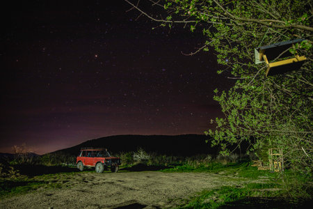 Night starry sky over a small village with an old red carの写真素材