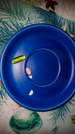 white and colored pills on blue plate stand on the table, medicine, vitamins, daily intake, half, treatmentの写真素材