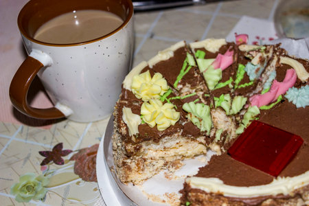 sliced chocolate cake with cream, cup of coffee, dessert, on the table, decorated, black icing,...