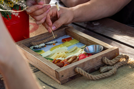 people try cheeses, prick with toothpicks, wooden board with different types, assortment of cheeses, snacksの写真素材