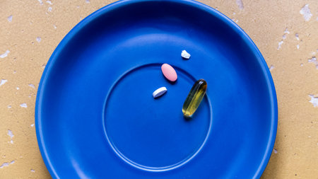 several tablets, capsules of different shapes, colors, on blue plate, pink, oval, white, transparent yellow, gel, white piece,の写真素材