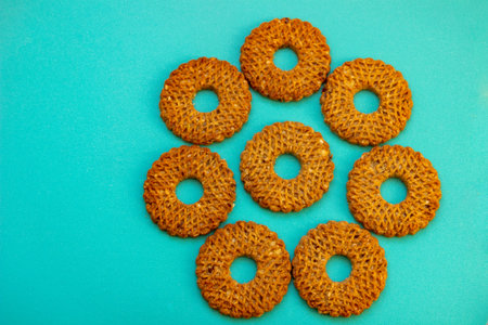 homemade cereal cookies, crushed nuts, classic round shape, hole in middle, brightblue-turquoise surface, contrast with elements, appetizing composition, bakingの写真素材