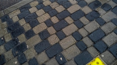 water flows on city street on gray cobblestones, tactile tiles of bright yellow color, marking,の写真素材