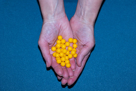 yellow round vitamin pills on woman's palms, hands holding vitamins, useful, dietary supplements, daylight, foodの写真素材