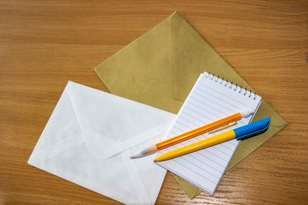 set of stationery on table, yellow-blue ballpoint pen and orange mechanical pencil on notebook,