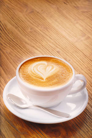 Cup of fresh cappuccino coffee on the wooden tableの写真素材