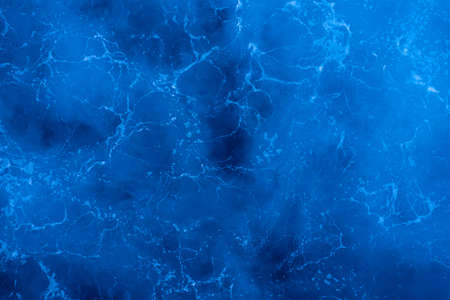 Dark blue deep sea surface, rippled water with sea foam and sparkling light