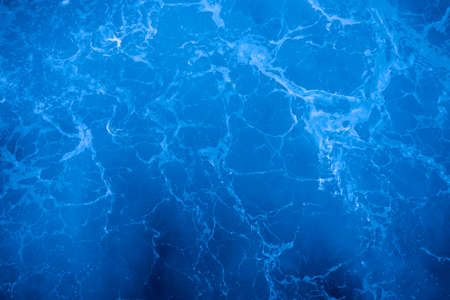 Dark blue deep sea surface, rippled water with sea foam and sparkling lightの写真素材