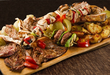 Rustic tray with various meats, mushrooms and assorted vegetables - isolated