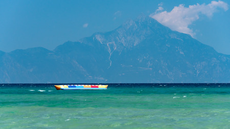Inflatable banana shaped boat at sunset on a calm sea, Mount Athos in the backgroundの写真素材