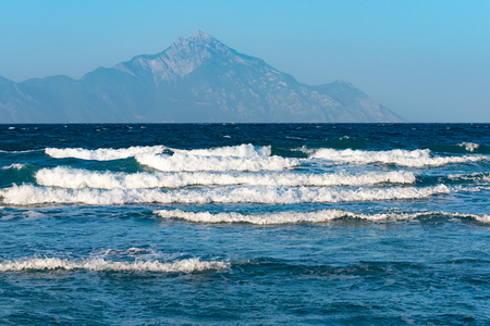 Sea waves crushing on the coast with Mount Athos in the backgroundの写真素材