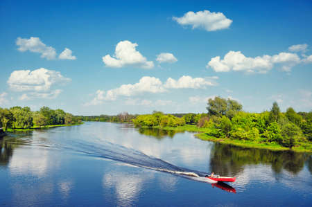 Landscape with a man and dog in a boat  flowing by the Narew river in Poland の写真素材