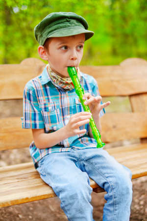 Young stylish kid plays on green recorderの写真素材