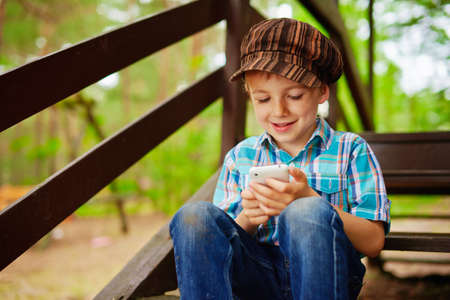 Young stylish boy browses internet on his mobile phoneの写真素材