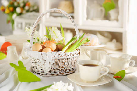 Easter basket full of eggs on a white festive table.の写真素材