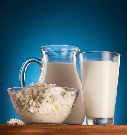 Jar and glass with milk and bowl with cottage cheese on a wooden table.の写真素材