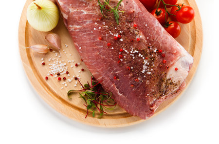 Raw pork meat with spices and vegetables on wooden board isolated on white backgroundの写真素材