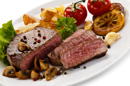 Grilled beefsteak with baked potatoes and mushrooms on white backgroundの写真素材
