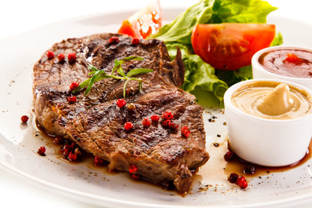 Grilled Beef Steak with Sauce and Vegetables on White Backgroundの写真素材
