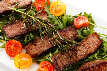Grilled beef with arugula and cherry tomatoes on a white backgroundの写真素材