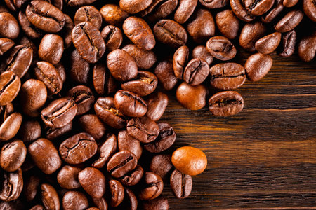Macro image of roasted coffee beans at brown textured wooden board background.の写真素材