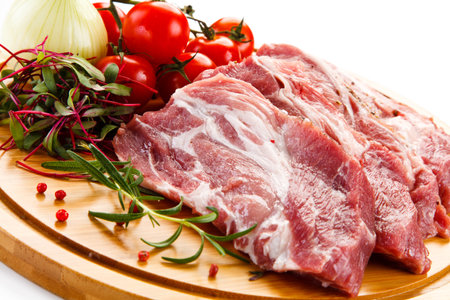 Raw pork meat with vegetables on a wooden board. Shallow dof.の写真素材
