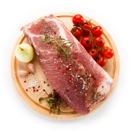 Raw pork meat with spices and vegetables on wooden board isolated on white backgroundの写真素材
