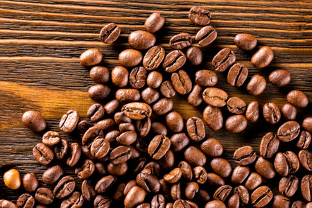 Macro image of roasted coffee beans at brown textured wooden board background.の写真素材