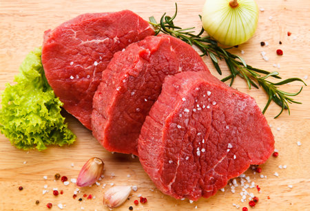fresh raw beef fillet with herbs and spices on wooden cutting boardの写真素材
