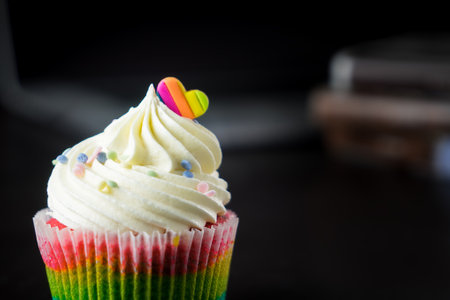 Rainbow cup cake on black background. Selective focus with shallow depth of field.の写真素材
