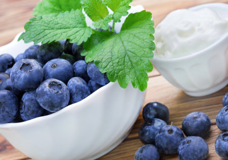 Fresh blueberries and sour cream on a wooden background. Healthy food.の写真素材