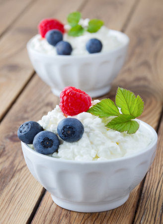 Cottage cheese with fresh berries in a bowl on a wooden tableの写真素材