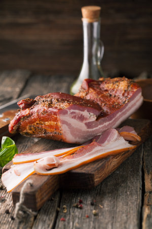 Delicious smoked bacon with spices on a wooden backgroundの写真素材