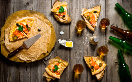 The pizza party. Pizza and beer for four people. On a wooden table. Top viewの写真素材