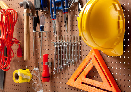 Peg board with hardhat, extension cord, flashlight, hammer, screw driver, caution tape, carpenter's...