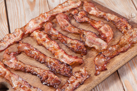 crispy sliced ethically raised organic bacon on a wooden plateの写真素材