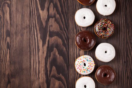 Donuts with colorful decor on wooden table. Top view with copy spaceの写真素材