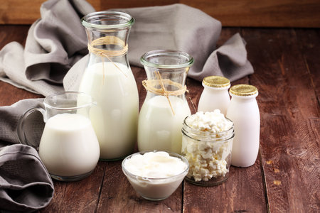 milk products - tasty healthy dairy products on a table on: sour cream in a white bowl, cottage cheese bowl, cream in a a bank and milk jar, glass bottle and in a glassの写真素材