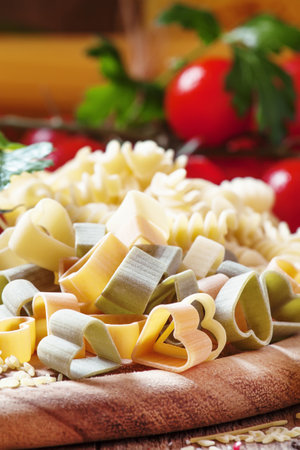 Dry pasta, three-colored hearts, vegetables and seasoning, selective focusの写真素材