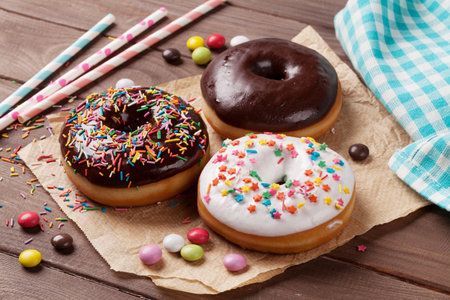 Donuts and candies on wooden tableの写真素材