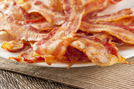 Cooked Greasy Bacon against a back groundの写真素材