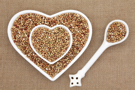 Buckwheat super food in heart shaped bowls and porcelain spoon over hessian background.の写真素材