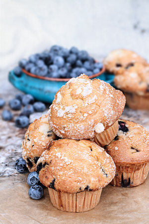 Delicious homemade blueberry muffins with fresh blueberries in the background.の写真素材