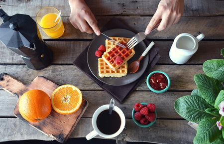 overhead photograph of person with breakfast waffles with marmalade, coffee and orange juiceの写真素材