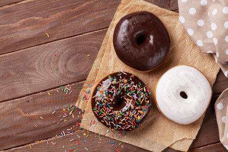 Colorful donuts on wooden table. Top view with copy spaceの写真素材
