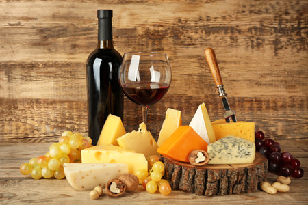 Red wine and stump with variety of cheese on wooden backgroundの写真素材