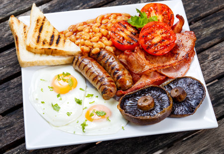 Full English breakfast with bacon, sausage, fried egg, baked beans and mushrooms.の写真素材