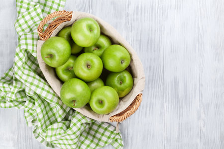 Green apples in basket over wooden table. Top view with copy spaceの写真素材