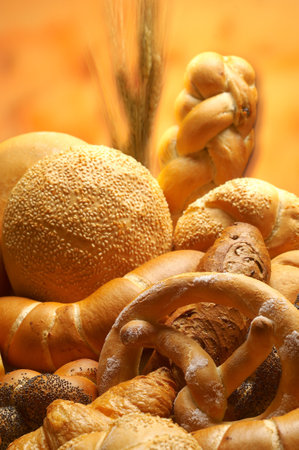assortment of baked bread on wooden table with ears of wheat backgroundの写真素材